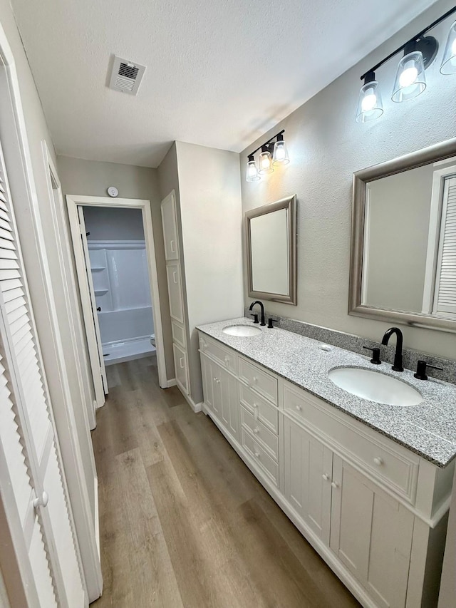 bathroom featuring wood-type flooring, a textured ceiling, and vanity