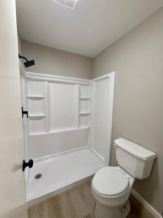 bathroom with hardwood / wood-style flooring, toilet, and walk in shower