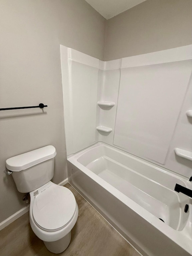 bathroom with wood-type flooring, shower / bathing tub combination, and toilet