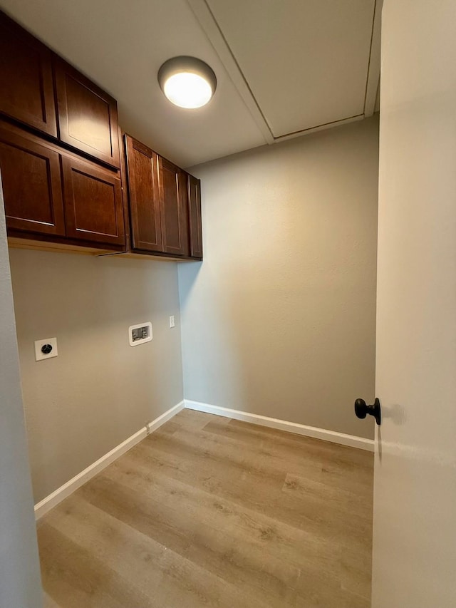 clothes washing area featuring cabinets, electric dryer hookup, washer hookup, and light wood-type flooring