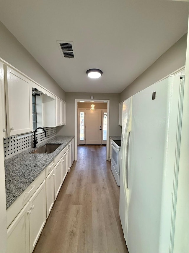 kitchen featuring sink, white cabinetry, light stone counters, light hardwood / wood-style flooring, and white appliances