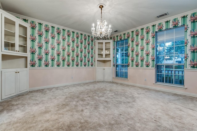 carpeted spare room featuring crown molding and an inviting chandelier