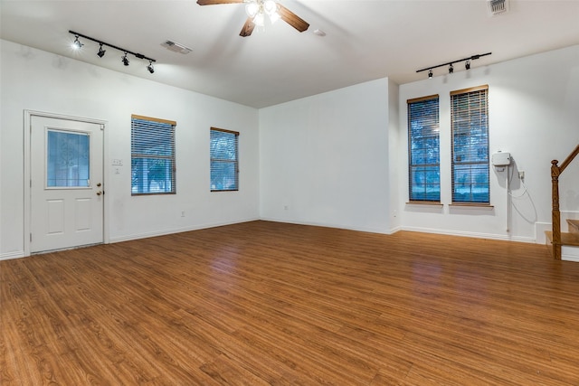 unfurnished living room featuring rail lighting, hardwood / wood-style floors, and ceiling fan