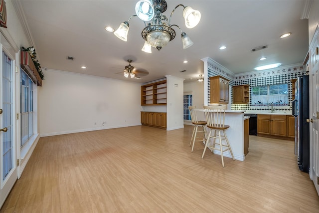 kitchen with sink, a breakfast bar area, light hardwood / wood-style floors, kitchen peninsula, and crown molding