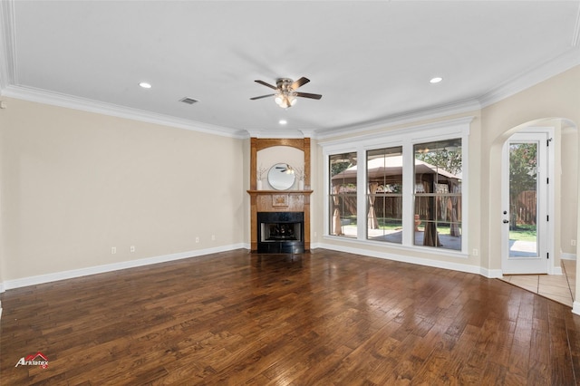 unfurnished living room with wood-type flooring, ornamental molding, ceiling fan, and a fireplace