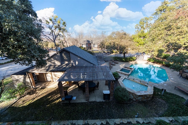 exterior space with a patio area, a pool with connected hot tub, and fence