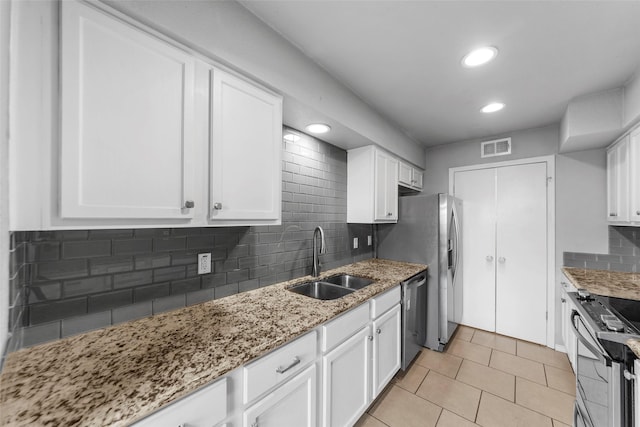 kitchen with stainless steel appliances, light stone countertops, sink, and white cabinets