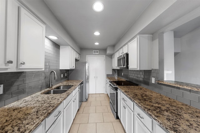 kitchen with dark stone countertops, appliances with stainless steel finishes, sink, and white cabinets