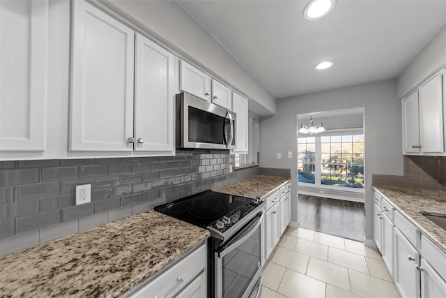 kitchen with white cabinetry, appliances with stainless steel finishes, light stone counters, and decorative backsplash