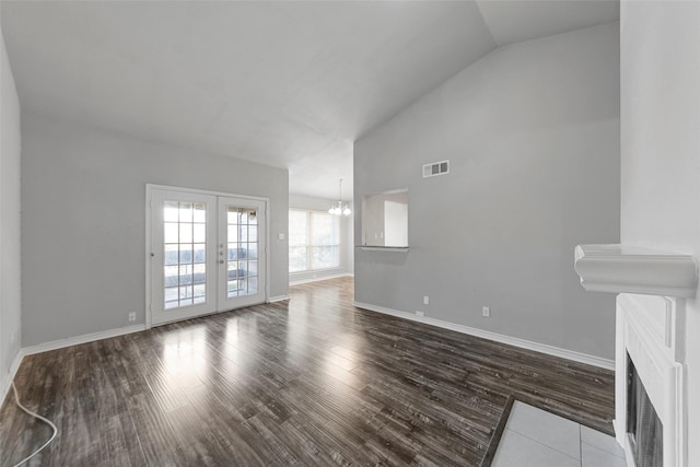 unfurnished living room with vaulted ceiling, a notable chandelier, dark hardwood / wood-style flooring, and french doors