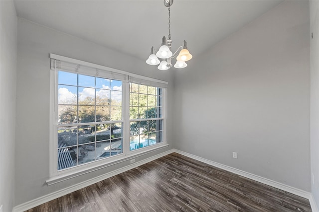 unfurnished dining area with dark hardwood / wood-style floors, a chandelier, and vaulted ceiling