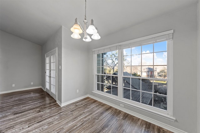 unfurnished dining area with dark wood-type flooring, vaulted ceiling, and a notable chandelier