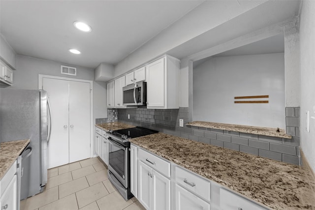 kitchen with stainless steel appliances, white cabinetry, tasteful backsplash, and light stone counters