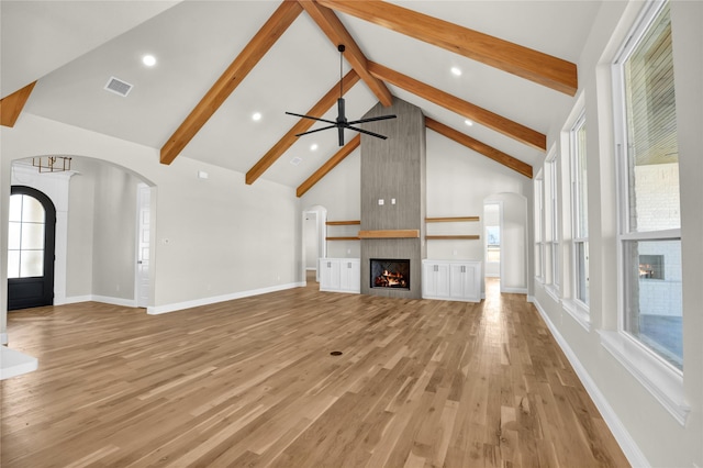 unfurnished living room featuring beamed ceiling, a fireplace, high vaulted ceiling, and light hardwood / wood-style flooring