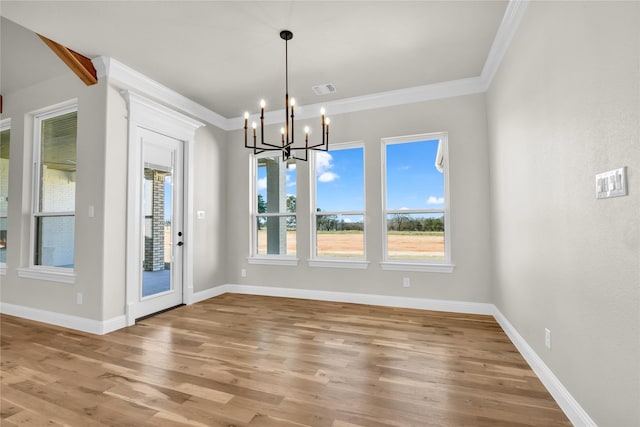 unfurnished dining area featuring crown molding, wood-type flooring, and a chandelier