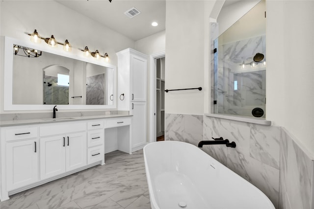 bathroom featuring vanity, independent shower and bath, and tile walls