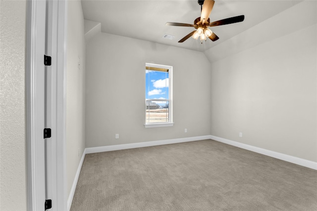 empty room with vaulted ceiling, ceiling fan, and light colored carpet