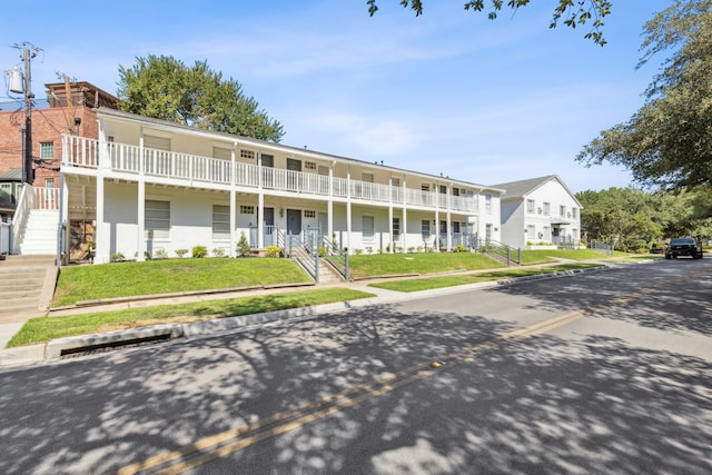 view of front of house with a balcony and a front lawn