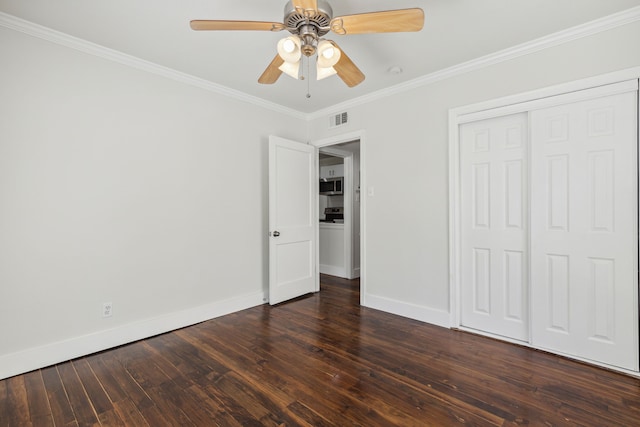 unfurnished bedroom with ceiling fan, ornamental molding, dark hardwood / wood-style flooring, and a closet