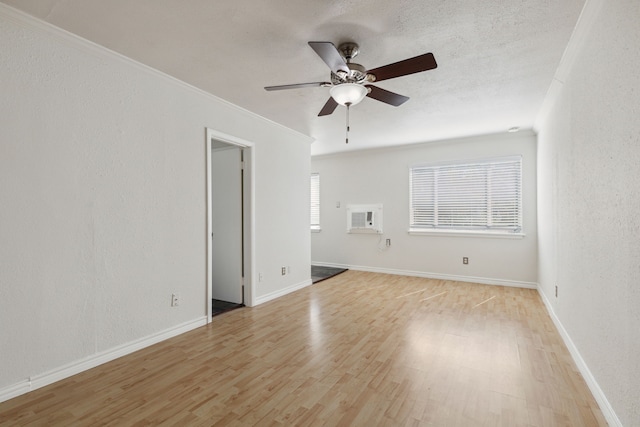 spare room featuring light hardwood / wood-style flooring, ceiling fan, a wall unit AC, ornamental molding, and a textured ceiling