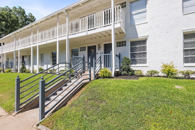 view of front of house with a balcony and a front lawn