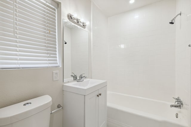 full bathroom featuring tiled shower / bath, vanity, and toilet