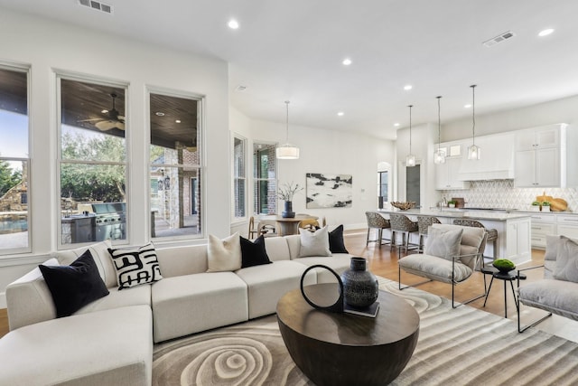 living room featuring ceiling fan, sink, and light hardwood / wood-style floors