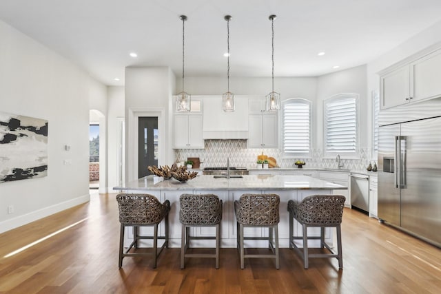 kitchen with premium range hood, appliances with stainless steel finishes, a center island, white cabinets, and decorative backsplash