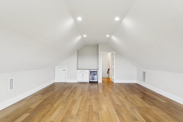 bonus room with lofted ceiling, wine cooler, and light wood-type flooring