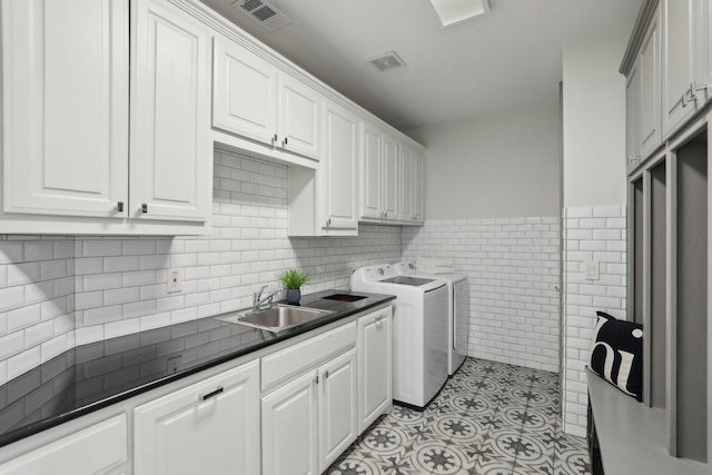 washroom with sink, tile walls, cabinets, light tile patterned floors, and washer and clothes dryer