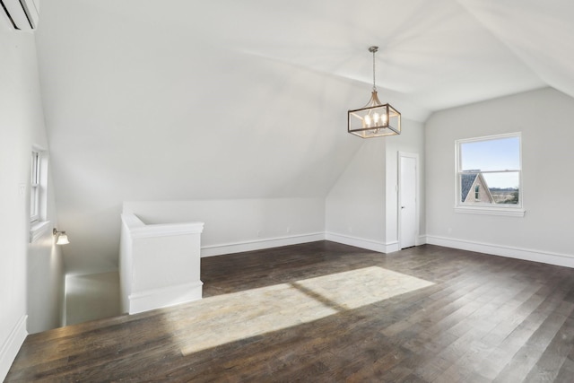 bonus room with lofted ceiling, dark wood-type flooring, an inviting chandelier, and a wall unit AC