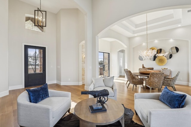 interior space with an inviting chandelier, a towering ceiling, a wealth of natural light, and light hardwood / wood-style floors