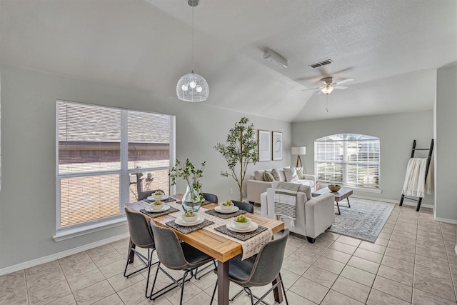 dining space with lofted ceiling, light tile patterned floors, a textured ceiling, and ceiling fan