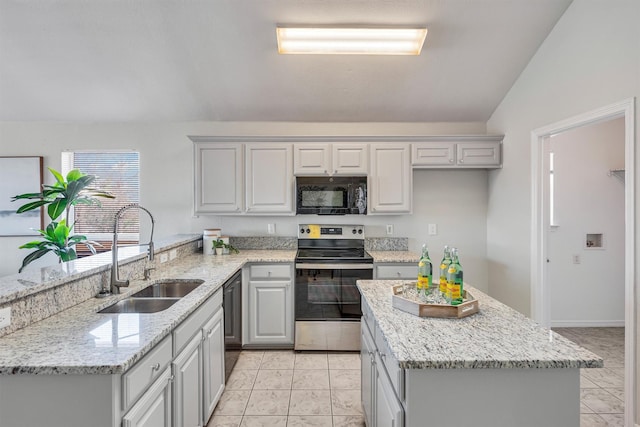 kitchen with lofted ceiling, sink, light stone counters, and black appliances