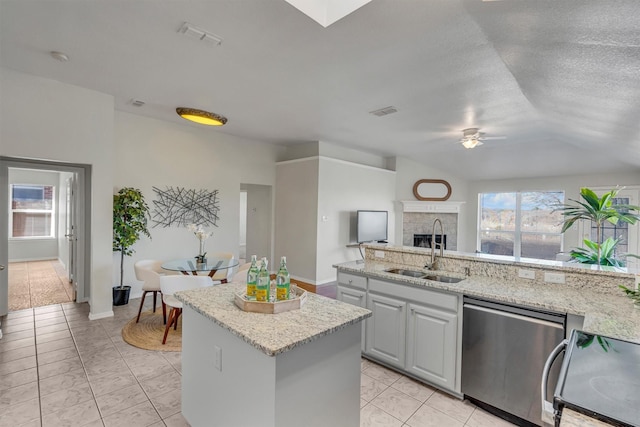 kitchen featuring electric stove, sink, light stone counters, a kitchen island, and stainless steel dishwasher