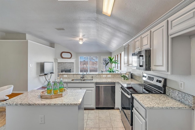 kitchen featuring sink, light stone counters, a textured ceiling, ceiling fan, and stainless steel appliances