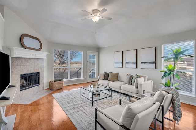 living room featuring ceiling fan, lofted ceiling, a fireplace, and light hardwood / wood-style floors