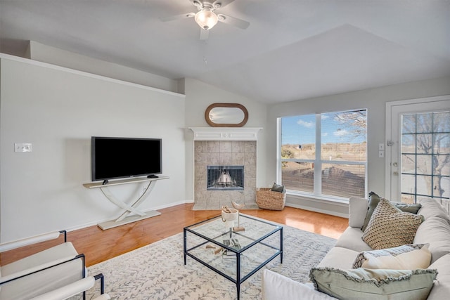 living room with hardwood / wood-style floors, vaulted ceiling, a tile fireplace, and plenty of natural light