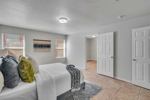 tiled bedroom featuring multiple windows and a textured ceiling