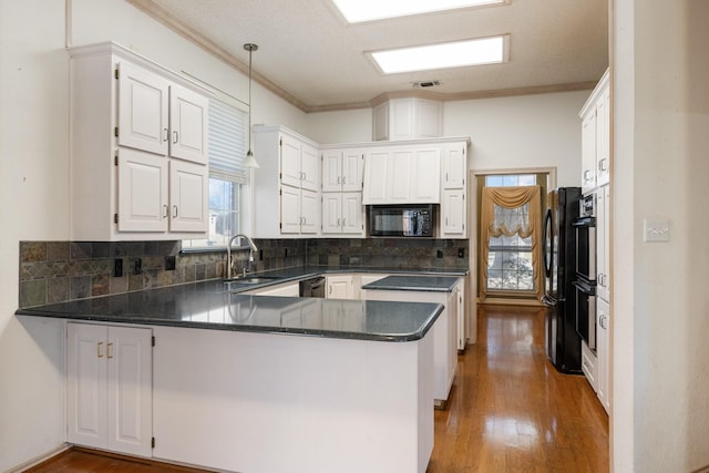 kitchen with crown molding, wood finished floors, a sink, black appliances, and a peninsula