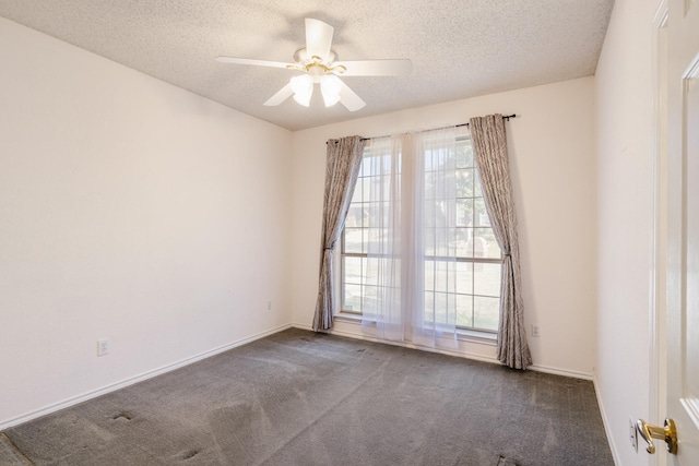 empty room featuring dark colored carpet, ceiling fan, a textured ceiling, and baseboards