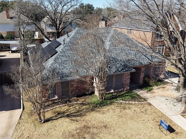 exterior space with a chimney, a lawn, and roof with shingles