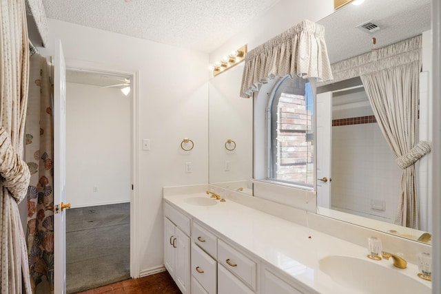 full bath with visible vents, a sink, a textured ceiling, and double vanity