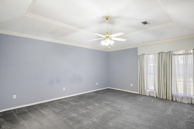 empty room with dark colored carpet, a raised ceiling, visible vents, and crown molding