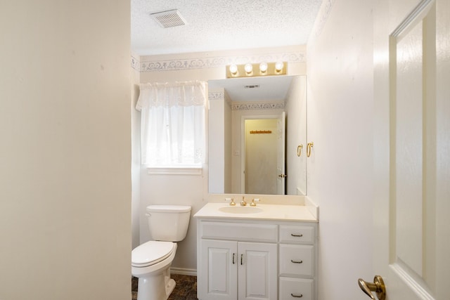 bathroom featuring visible vents, toilet, a textured ceiling, and vanity