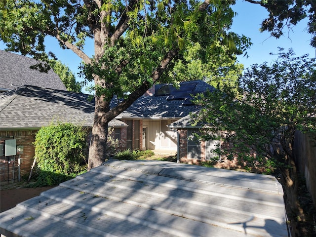 view of front of home featuring brick siding and roof with shingles