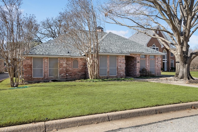 single story home with a shingled roof, brick siding, and a front lawn