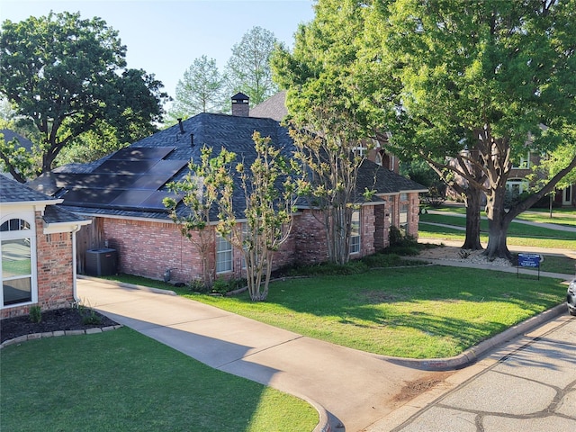 view of side of property featuring a lawn, a chimney, a shingled roof, and brick siding