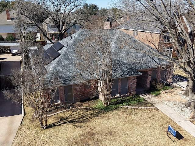 view of side of property with a shingled roof, a chimney, and brick siding