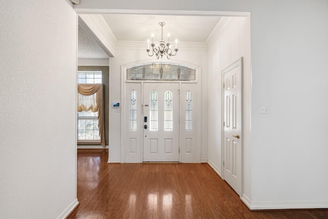 entrance foyer featuring a chandelier, crown molding, baseboards, and wood finished floors